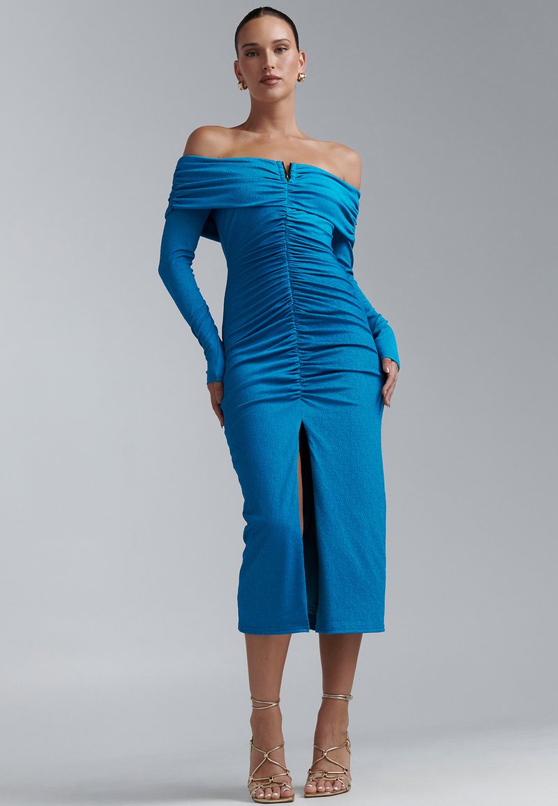 Robe bleue épaules dénudées avec manches longues, texture froncée, fente à l'avant et petit détail métallique au niveau de l'encolure.