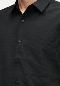 Μαύρο υφασμάτινο πουκάμισο με υφή, με γιακά και τσέπη στο στήθος που φέρει το μικρό λογότυπο «cK» στο ύφασμα.