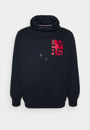 Schwarzer Hoodie mit Fronttasche, Kordelzug und rotem Aufdruck mit dem Schriftzug "HILFIGER 1985" auf der oberen linken Brust.