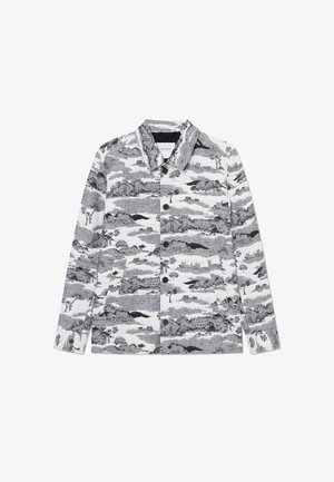 Fekete-fehér mintás dzseki, galléros nyakkal, gombos elülső záródással és két oldalsó zsebbel. A dizájn tájképi motívumokat tartalmaz.