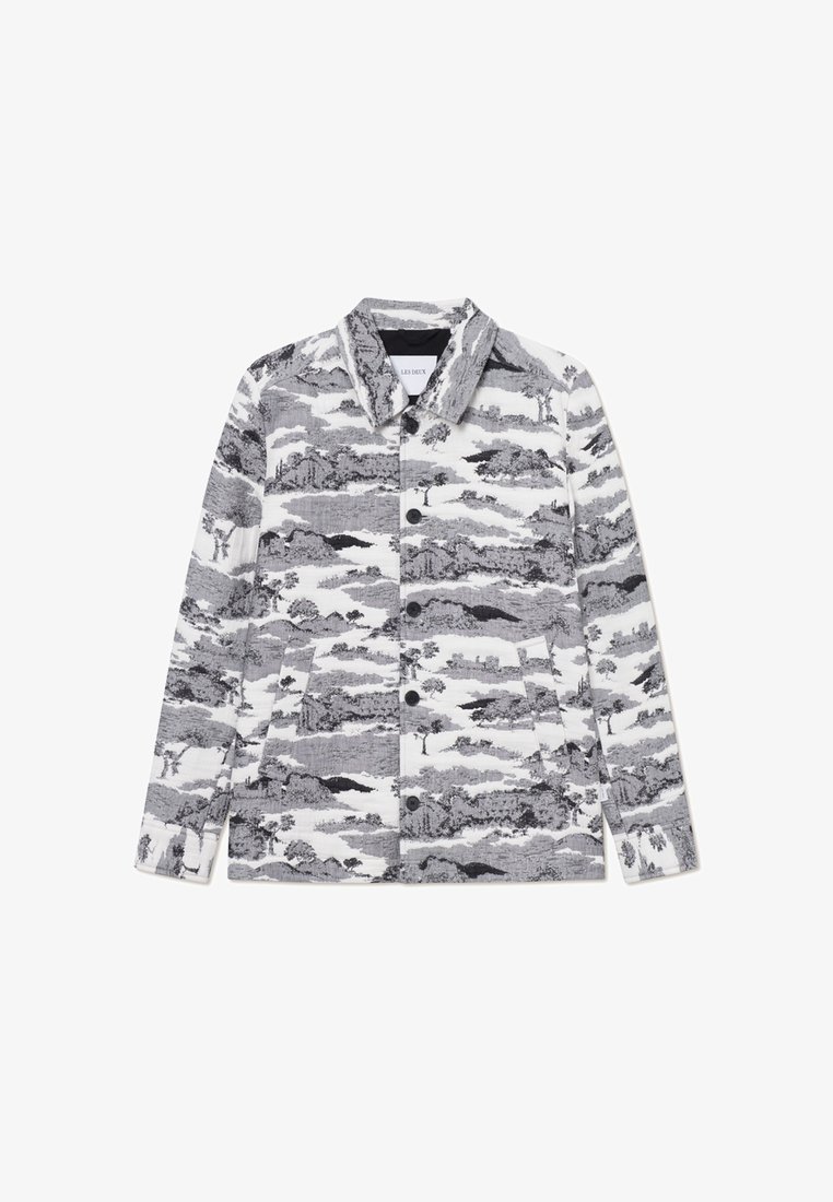 Giacca a motivi in bianco e nero con colletto, chiusura con bottoni e due tasche laterali. Il design include immagini di paesaggi.