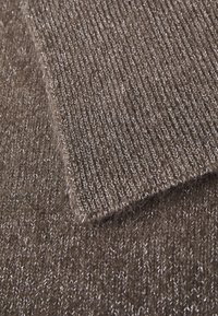 Brun stickad tyg med en mjuk textur, som har en subtil lyster och en närbild av de vävda trådarna och mönster detaljer.