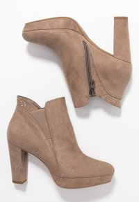 Beige mokkasiinibootid kõrge ploki kontsaga, külgzipper ja dekoratiivne õmblus ääres. Sile tekstuur ja ümarad varbad.