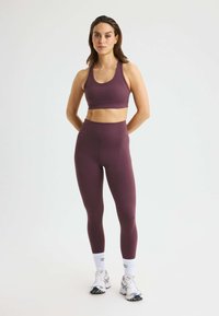 Bordeaux sportbh en high-waisted leggings van rekbare stof, gecombineerd met witte sokken en sportschoenen. Eenvoudig ontwerp, getailleerde pasvorm.