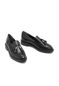 Svarta läderloafers med tofsar på toppen, rund tå och låg klack i staplad design, visade mot en vit bakgrund.