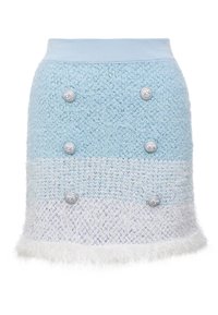 Ljusblå stickad kjol med ett texturerat mönster, prydd med silverknappar och en fluffig vit manschett, designad i en utsvängd form.