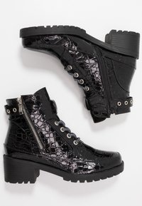 Bottines en cuir verni noir avec une texture en relief croco, détails de fermeture éclair, œillets en métal et un talon épais. Comprend un design à lacets.