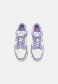 Paire de baskets Nike blanches et lavande avec des logos swoosh roses, vues de dessus sur un fond gris clair.