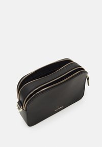 Borsa a tracolla nera in pelle con due zip dorate e un piccolo logo dorato "Ted Baker" sulla parte anteriore.