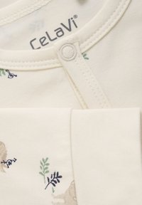 Beige bomuldsoutfit med trykknaplukning, subtile grønne og blå blomster mønstre, og "CelaVi" mærket trykt indeni.
