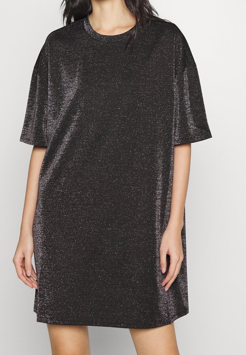 Robe noire à manches courtes en tissu scintillant, présentant une coupe décontractée et un col rond, avec une texture lisse et un léger éclat.