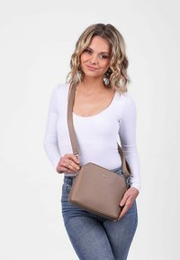 Béžová syntetická crossbody taška se strukturovaným tvarem, nastavitelným popruhem a embosovaným logem. Hladký povrch bez viditelných vzorů.