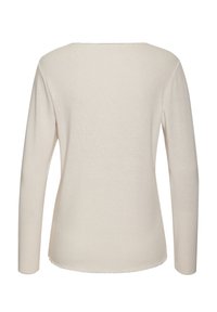 Light beige long-sleeve top with a round neckline, soft texture, and a slightly curved hem. Clean design with no prominent patterns or accents.