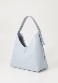 Sac à main en cuir bleu clair avec une forme triangulaire courbée, une bandoulière ajustable et un design minimaliste. L'intérieur présente une couleur contrastante.