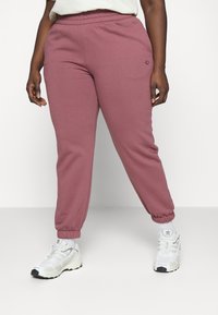 Vaatekappaleet vaaleanpunaiset collegehousut jotka on varustettu joustavalla vyötäröllä ja kuminauhakäärmeillä, valmistettu pehmeästä kankaasta. Yhdistetty valkoisiin urheilukenkiin, joissa on harmaita yksityiskohtia.