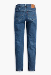 Jean en denim bleu avec jambes droites, deux poches arrière, surpiqûres orange et une étiquette de marque en cuir marron sur la ceinture.