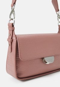 Borsa a tracolla in finta pelle rosa con superficie testurizzata, chiusura a patta e dettaglio in hardware silver. Tracolla regolabile con attacchi a clip.