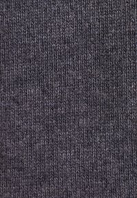 Gros plan d'un tissu en laine tricotée gris foncé montrant un fil doux et épais avec un motif de point vertical côtelé.
