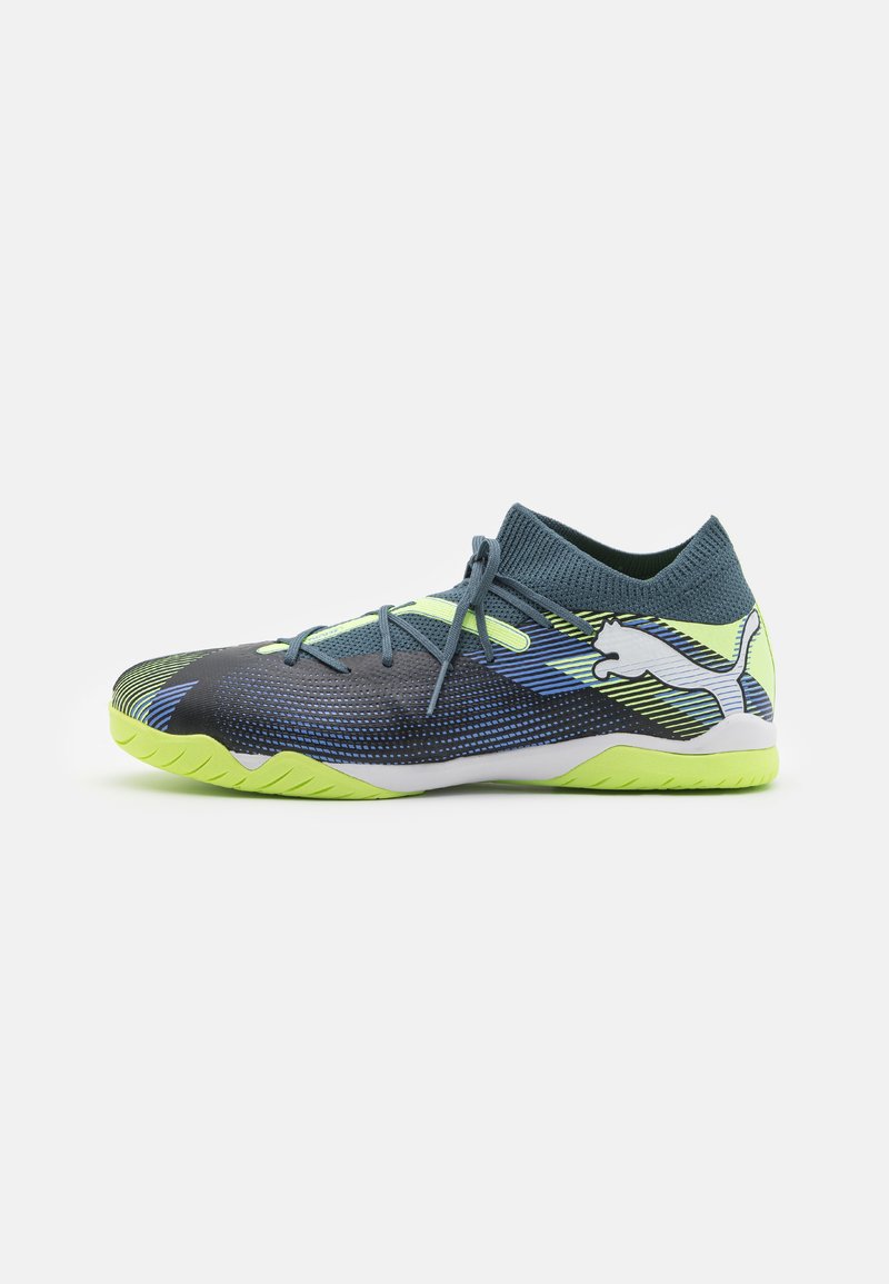 Scarpa sportiva di colore blu scuro e verde con una tomaia testurizzata, accenti al neon, un collare simile a una calza e una suola decorata con dettagli gialli e bianchi.