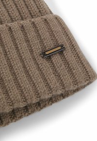 Strikket brun hue med lodret ribbet mønster, der har en sort metalaccentplade med en guldstribe. Blød tekstur med folded cuff.