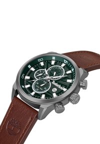 Orologio rotondo d'argento con un quadrante verde scuro texturizzato, tre quadranti secondari, marcatori delle ore bianchi e un cinturino in pelle marrone. Logo Timberland in rilievo.