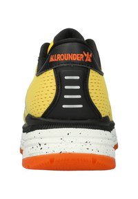 Gelbe Sportschuhe mit schwarzen Akzenten, ausgestattet mit einem Obermaterial aus Mesh, einer strukturierten Zwischensohle, einer gesprenkelten weißen Gummisohle und reflektierenden Details.