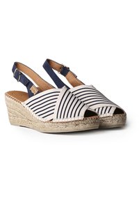 Espadrille con tacco a trapezio e cinturino. Presenta una tomaia in tessuto a righe beige e blu navy, suola avvolta in juta e dettagli in pelle.