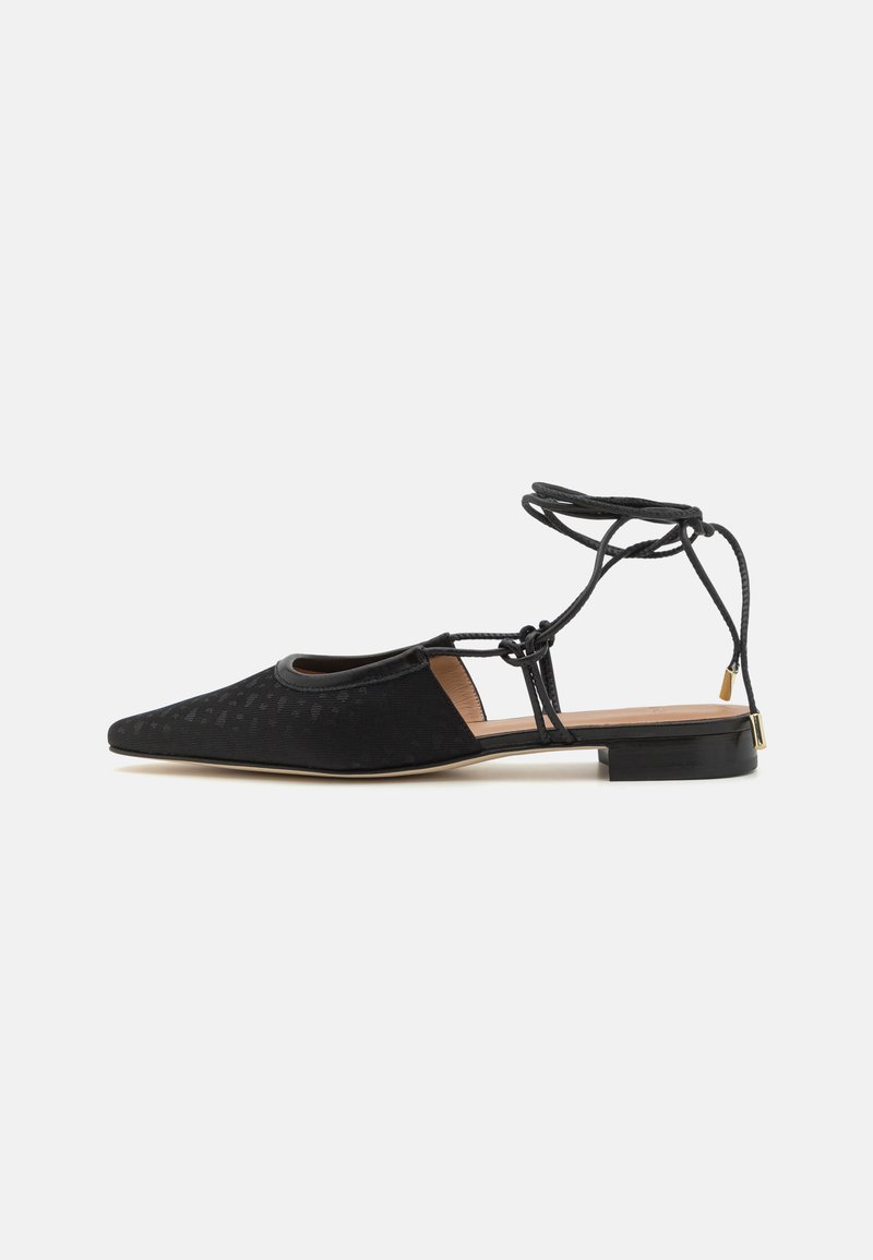 Zapato plano negro con punta afilada, parte superior texturizada, lazos en los tobillos y un tacón bajo cuadrado. Presenta un patrón sutil en el material.