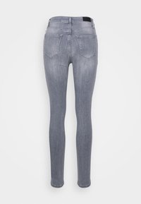 Jeans skinny em denim cinza claro, com uma textura suave, design de cinco bolsos e um patch com logo na cintura.