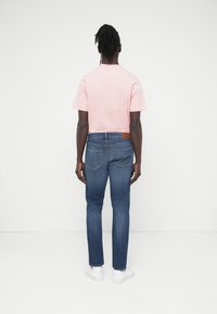 Ροζ και λευκή ρ ιγέ κοντομάνικη μπλούζα συνδυασμένη με μπλε τζιν παντελόνια. Τα τζιν έχουν τσέπες στο πίσω μέρος και καφέ δερμάτινη ετικέτα στη μέση.