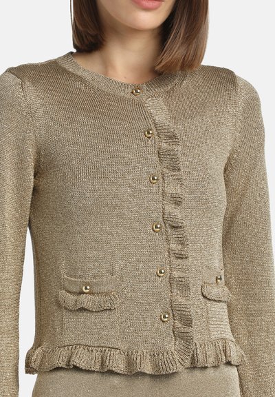 Auksinės tekstūros kardiganas suapvalintu kaklu, raukšlėta priekiu, dviem kišenėmis ir auksinės spalvos mygtukais. Megztas audinys su švelniu blizgesiu.