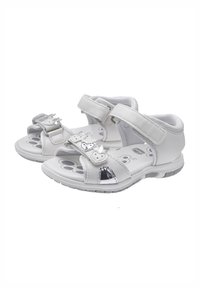 Sandali bianchi con cinturini regolabili in velcro, soletta testurizzata e dettagli metallici. Progettati con punta aperta e suola imbottita.