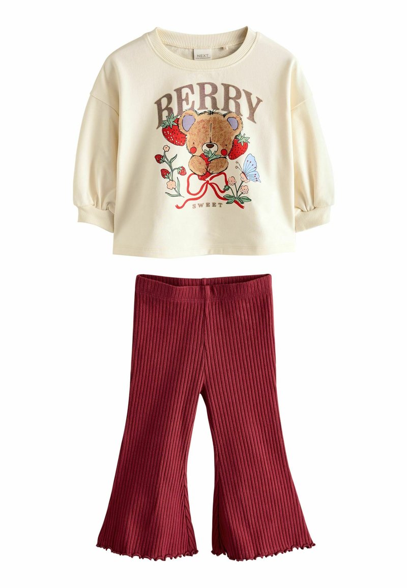 Cremefarvet sweater med puffærmer, prydet med en bjørnegrafik, som er parret med bordeaux ribbede flared bukser. Blødt, afslappet stof i et legende design.