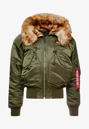 Veste bomber verte olive avec un col en fausse fourrure, fermeture éclair, deux poches avant et une étiquette indiquant "ENLEVER AVANT LE VOL".