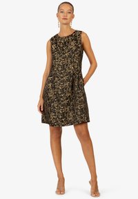 Robe noire avec motif de feuilles dorées, sans manches, encolure ronde et poches latérales. Tissu texturé avec un corsage ajusté.