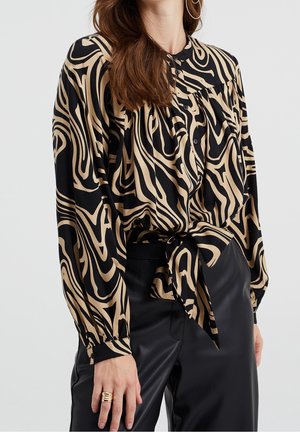 Blusa de manga larga negra y beige con un patrón abstracto en espiral, botón frontal, escote fruncido y detalle de cintura atada.