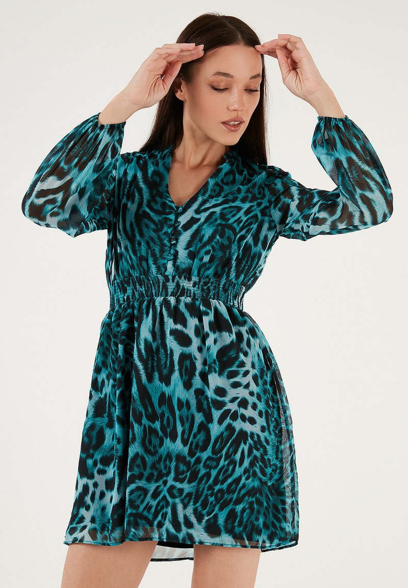 Türkises Leopardenmuster-Kleid aus transparentem Stoff. Über Knopfverschluss, elastischer Taille und langen Puffärmeln mit elastischen Bündchen.