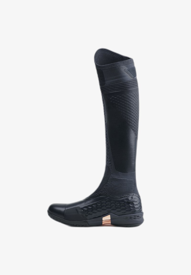 Botte noire en caoutchouc montant jusqu'au genou, imperméable, fabriquée en matériau texturé et flexible. Présente un embout lisse, un motif en nid d'abeille sur la partie inférieure et un accent métallisé.