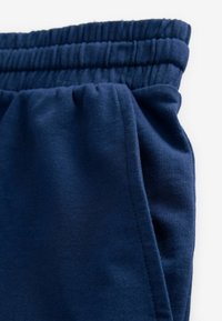 Pantalones de chándal azul marino con cinturilla elástica, fabricados en material suave, que presentan una textura lisa y detalles de costura visibles.