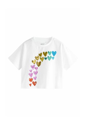 Camiseta corta blanca con un patrón colorido de brillantes formas de corazones en lentejuelas doradas, turquesa, rosa, naranja y púrpura en el frente.