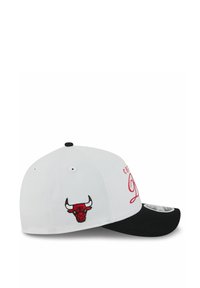Weißer Hut mit schwarzem Schirm, der das rot gestickte Logo der Chicago Bulls und geschwungene Schriftzüge zeigt. Das Material wirkt glatt, mit einem strukturierten Design.