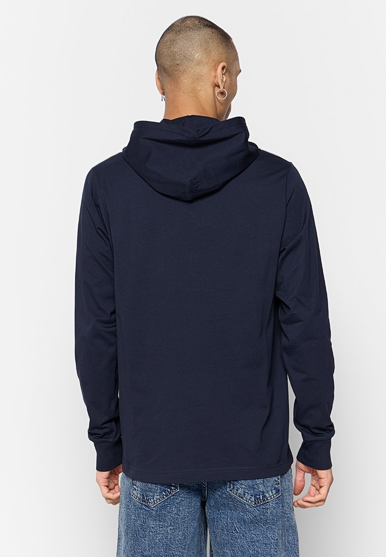 Marineblauwe hoodie met lange mouwen en een trekkoord aan de capuchon, gemaakt van zacht materiaal. Kenmerkt een eenvoudige uitstraling en een losse pasvorm, gecombineerd met lichte jeans.