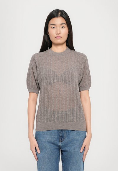 Maglione a maniche corte lavorato a maglia marrone chiaro con un motivo testurizzato, colletto e orlo a coste, abbinato a jeans in denim blu.