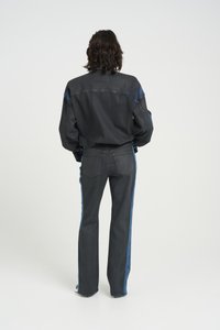 Denim jacket and jeans set in dark gray, featuring blue side stripes. The fabric is slightly textured with a structured silhouette.