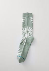 Calzino verde con motivo di foglie bianche, polsino a costine e accentuazione blu sulla punta. Realizzato in morbido materiale tessile, progettato per il comfort.