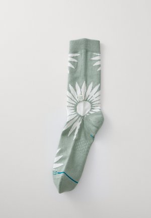 Calzino verde con motivo di foglie bianche, polsino a costine e accentuazione blu sulla punta. Realizzato in morbido materiale tessile, progettato per il comfort.