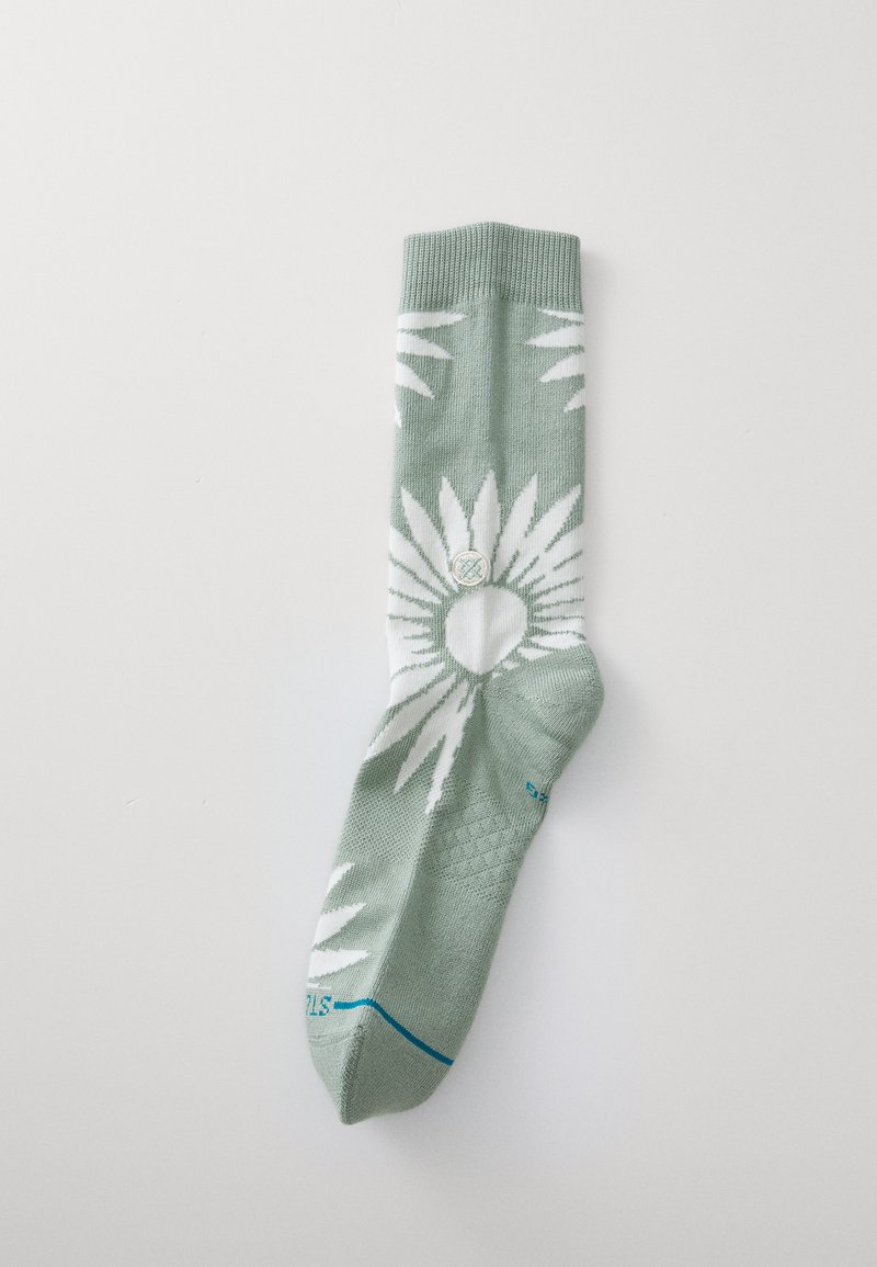 Calzino verde con motivo di foglie bianche, polsino a costine e accentuazione blu sulla punta. Realizzato in morbido materiale tessile, progettato per il comfort.