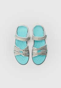 Teva sandals with a turquoise cushioned footbed, light gray adjustable straps, and a textured black rubber sole for grip.