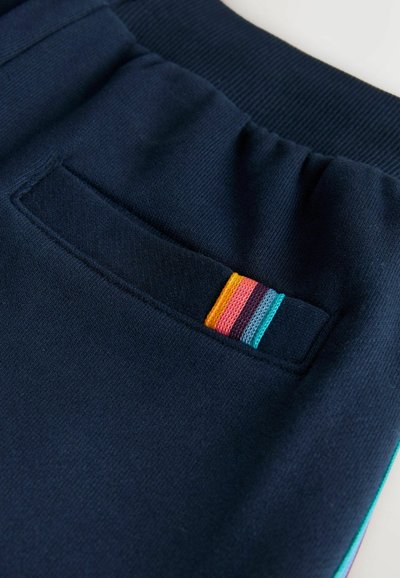 Bolsillo de tela azul marino con detalle de rayas coloridas en naranja, rosa, púrpura, azul y verde azulado en una prenda con cinturilla acanalada.