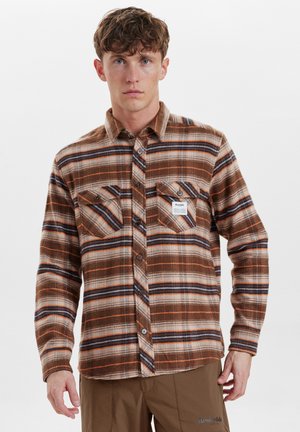 Bruine geruite flanellen shirt met oranje en blauwe strepen, voorzien van twee borstzakken en een label op de linkse zak. Zachte textuur, knoopsluiting.